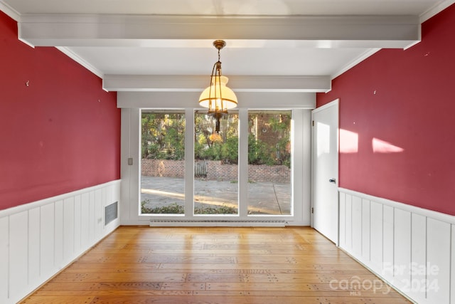 unfurnished dining area with baseboard heating, beamed ceiling, wood-type flooring, and ornamental molding