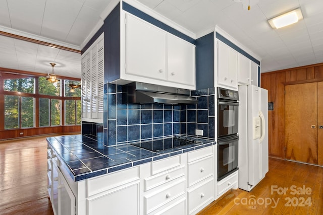 kitchen featuring tile countertops, light hardwood / wood-style flooring, black appliances, and exhaust hood