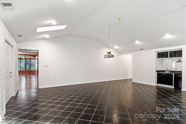 unfurnished living room featuring lofted ceiling with skylight, dark tile patterned floors, and sink