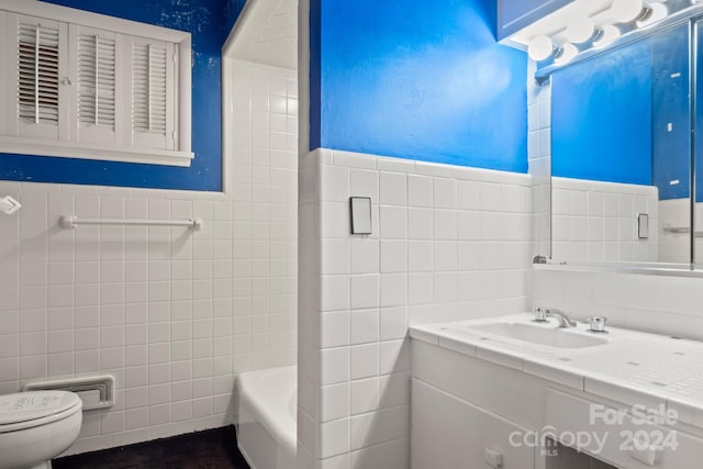 bathroom featuring vanity, a bath, toilet, and tile walls