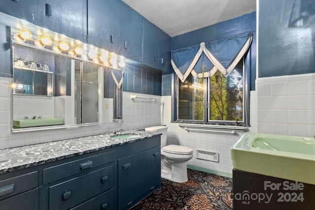 bathroom with tile patterned flooring, vanity, toilet, and tile walls