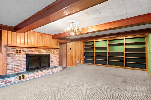 unfurnished living room with a fireplace, wood walls, beamed ceiling, and carpet