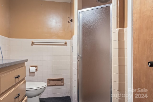 bathroom featuring vanity, toilet, tile walls, and walk in shower