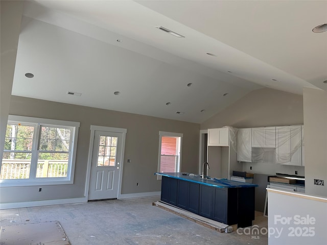 kitchen with high vaulted ceiling, white cabinetry, sink, a kitchen island with sink, and blue cabinetry