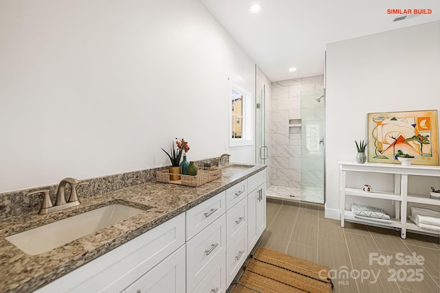 bathroom featuring double vanity, a stall shower, a sink, and recessed lighting