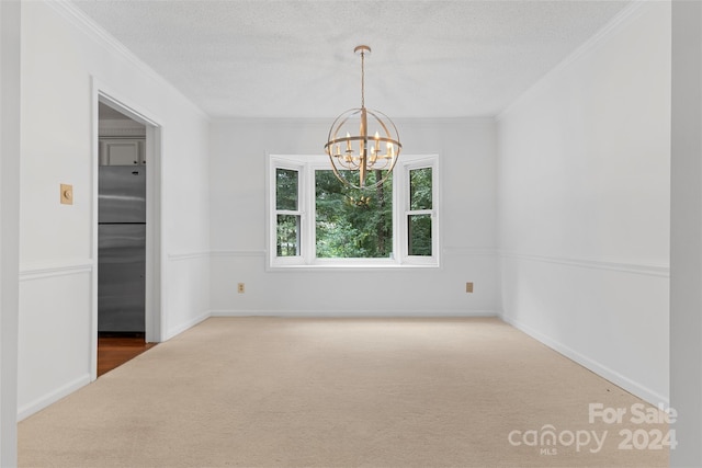 spare room with a textured ceiling, a chandelier, carpet flooring, and crown molding