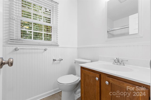 bathroom featuring a textured ceiling, tile patterned flooring, vanity, and toilet