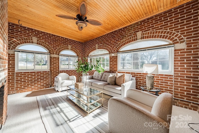 unfurnished living room featuring carpet flooring, ceiling fan, wooden ceiling, and brick wall