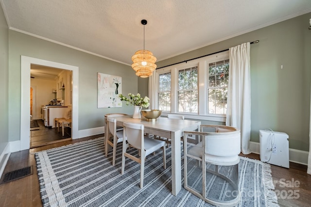 dining area with ornamental molding, a textured ceiling, dark hardwood / wood-style floors, and a notable chandelier