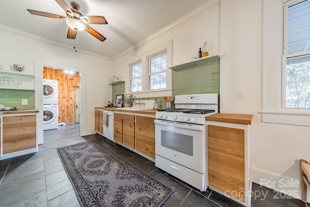 kitchen featuring crown molding, white appliances, stacked washer and dryer, and tasteful backsplash