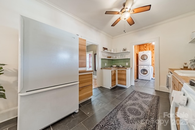 kitchen featuring ceiling fan, crown molding, white fridge, stacked washer / drying machine, and decorative backsplash