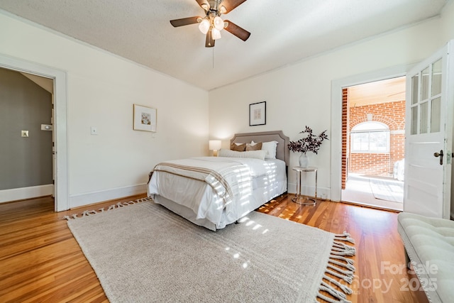 bedroom with ceiling fan, wood-type flooring, a textured ceiling, and access to outside