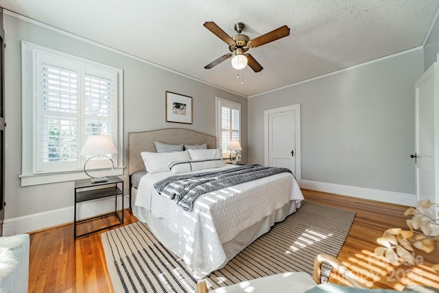 bedroom with hardwood / wood-style floors, ceiling fan, and crown molding