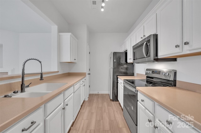 kitchen with white cabinetry, sink, stainless steel appliances, and light hardwood / wood-style flooring