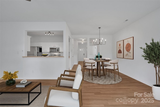 dining area featuring light wood-type flooring and a chandelier