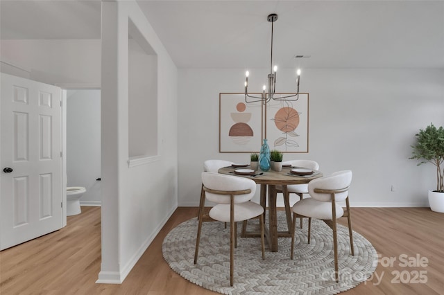 dining area with light hardwood / wood-style floors and a notable chandelier