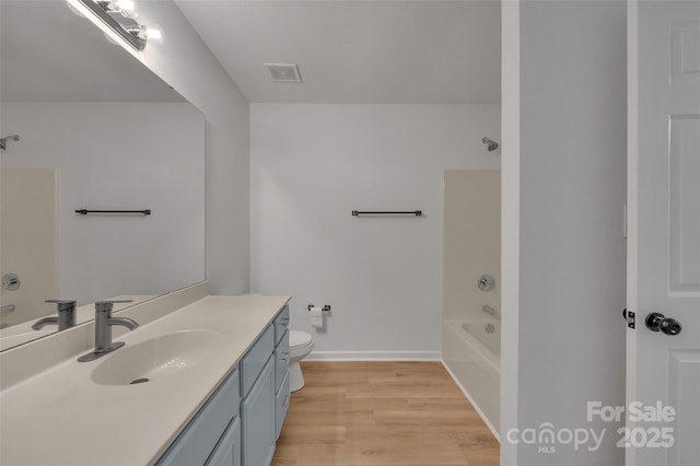 full bathroom with shower / bathing tub combination, vanity, hardwood / wood-style flooring, and toilet