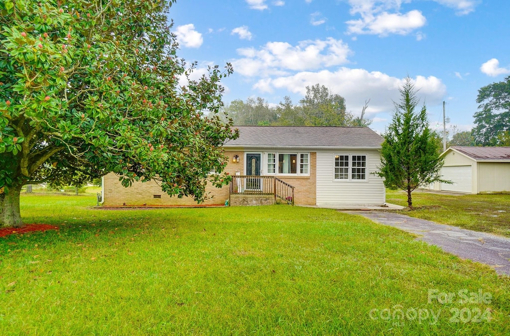 ranch-style house with a front lawn, an outdoor structure, and a garage