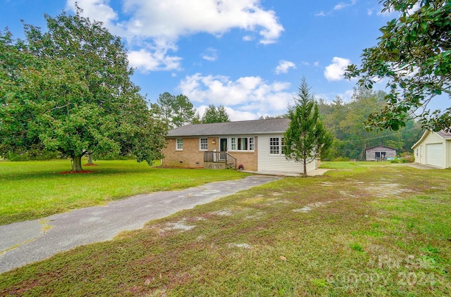 ranch-style house with a garage, a front lawn, and an outbuilding