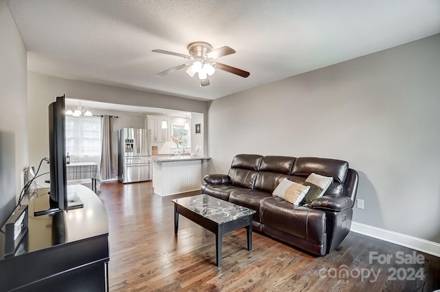 living room with ceiling fan, a textured ceiling, and dark wood-type flooring