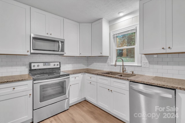 kitchen featuring dark stone counters, stainless steel appliances, white cabinetry, and sink