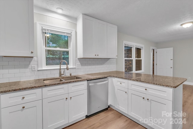 kitchen featuring light hardwood / wood-style floors, white cabinetry, kitchen peninsula, stainless steel dishwasher, and sink