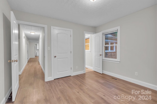 unfurnished bedroom featuring a textured ceiling, light hardwood / wood-style floors, and a closet