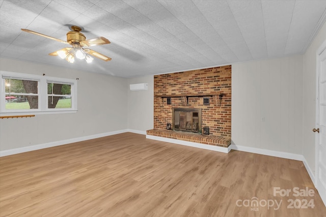 unfurnished living room featuring light hardwood / wood-style flooring, a brick fireplace, ceiling fan, and a wall mounted AC