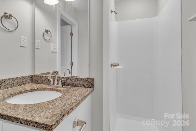 bathroom featuring walk in shower and vanity