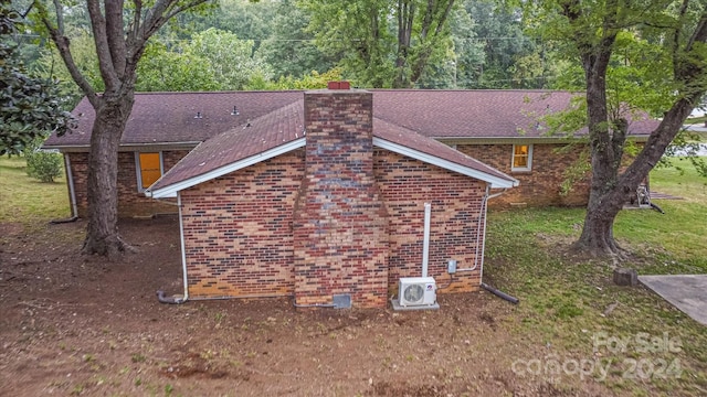 view of side of home with ac unit and a yard