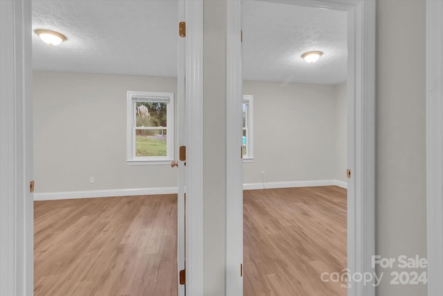 unfurnished room with a textured ceiling and light hardwood / wood-style floors