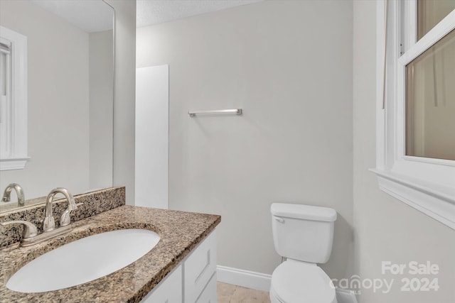 bathroom with a textured ceiling, vanity, toilet, and tile patterned floors