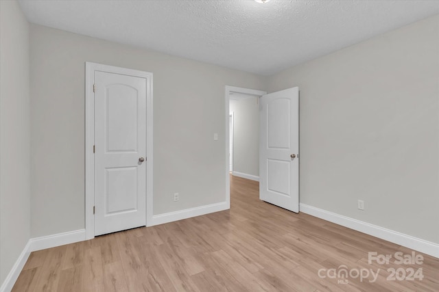 interior space featuring light wood-type flooring and a textured ceiling