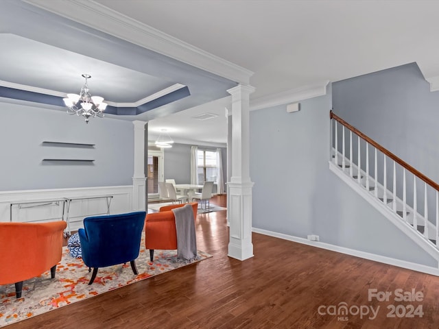 living room with dark hardwood / wood-style flooring, ornate columns, crown molding, a tray ceiling, and a chandelier