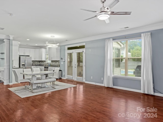 unfurnished dining area with dark hardwood / wood-style flooring, ornate columns, ceiling fan, french doors, and ornamental molding