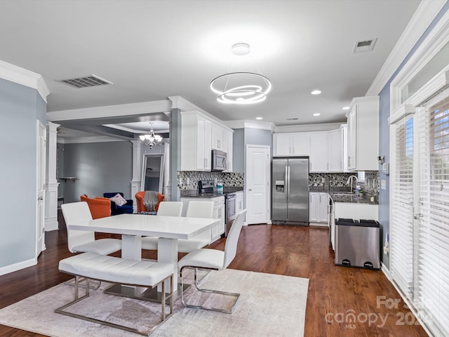 dining room with sink, crown molding, dark wood-type flooring, and a chandelier