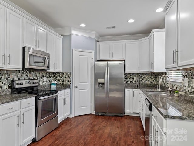 kitchen with appliances with stainless steel finishes, crown molding, dark wood-type flooring, and white cabinets