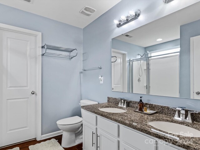 bathroom with vanity, hardwood / wood-style flooring, an enclosed shower, and toilet