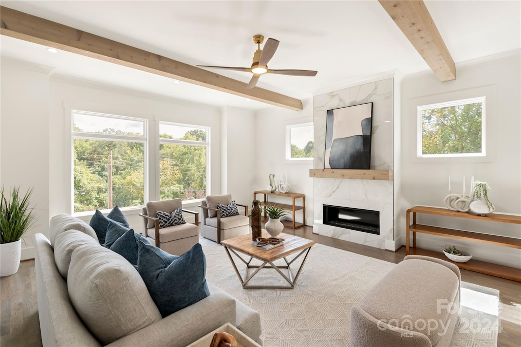 living room with a wealth of natural light, beam ceiling, a premium fireplace, and hardwood / wood-style flooring