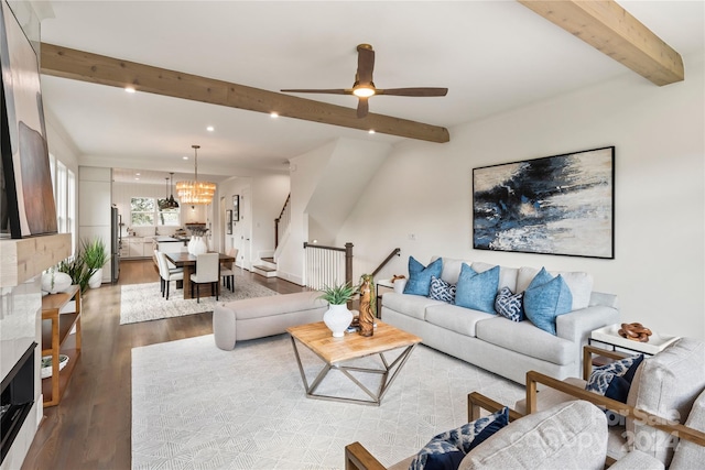 living room featuring ceiling fan with notable chandelier, beamed ceiling, and light wood-type flooring