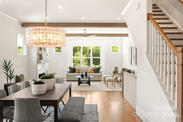 dining area with beamed ceiling, light hardwood / wood-style flooring, a premium fireplace, and plenty of natural light