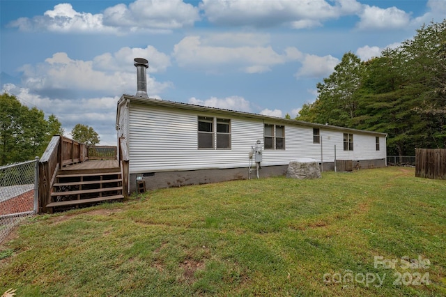 rear view of property featuring a wooden deck and a yard