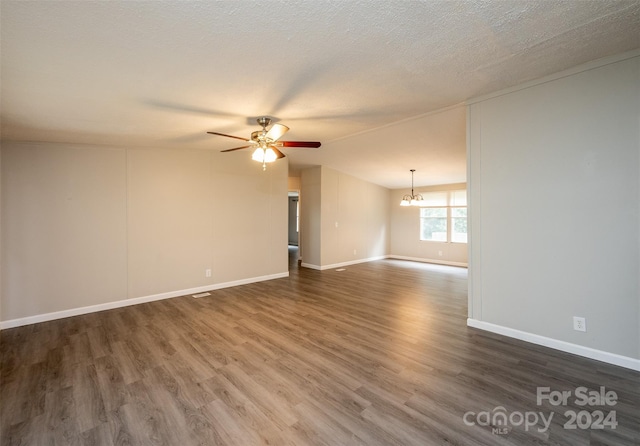 spare room featuring ceiling fan with notable chandelier, lofted ceiling, a textured ceiling, and dark hardwood / wood-style floors