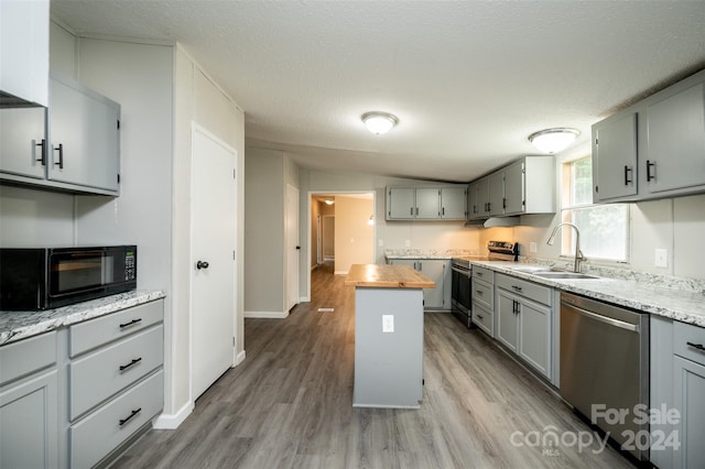 kitchen with appliances with stainless steel finishes, light hardwood / wood-style floors, wood counters, and sink