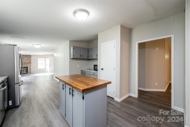 kitchen with gray cabinetry, stainless steel appliances, wood-type flooring, and butcher block counters