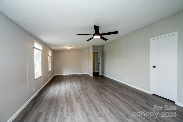 empty room featuring ceiling fan, a textured ceiling, and dark hardwood / wood-style floors