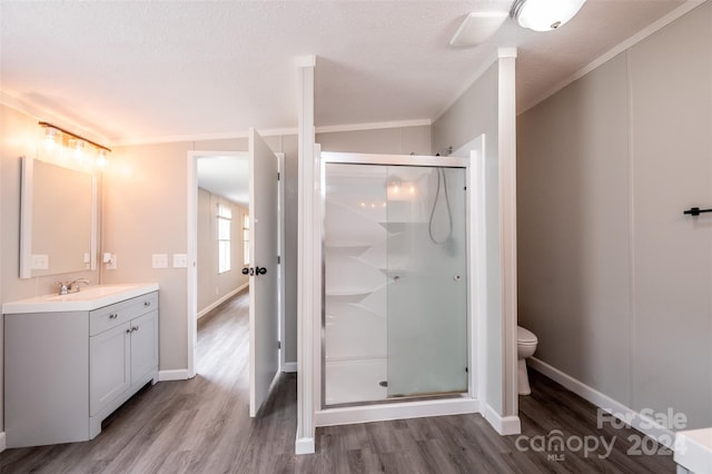 bathroom with vanity, wood-type flooring, crown molding, toilet, and a shower with door