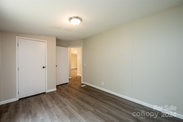 unfurnished bedroom featuring a textured ceiling and dark hardwood / wood-style floors