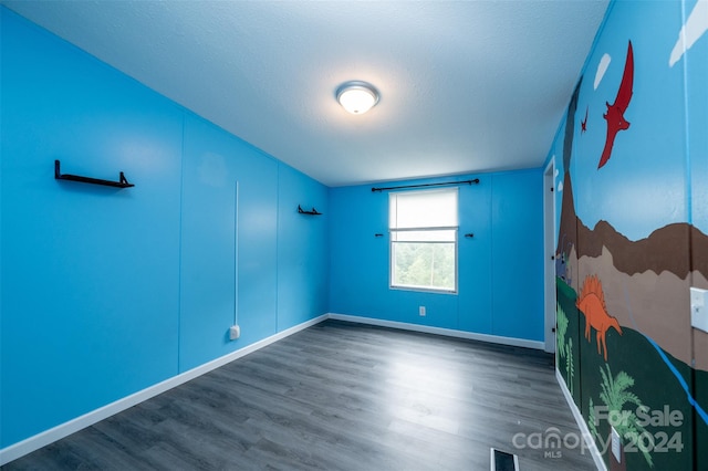 unfurnished room featuring a textured ceiling and dark wood-type flooring