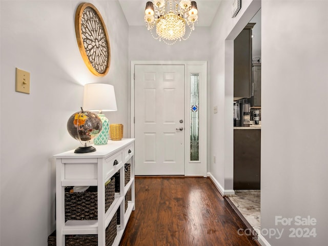 foyer entrance with an inviting chandelier and dark hardwood / wood-style flooring